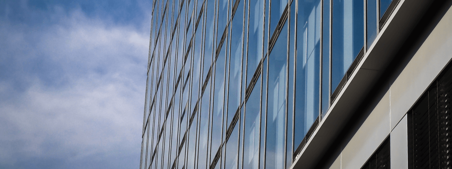The glass facade of a building next to a partly cloudy sky