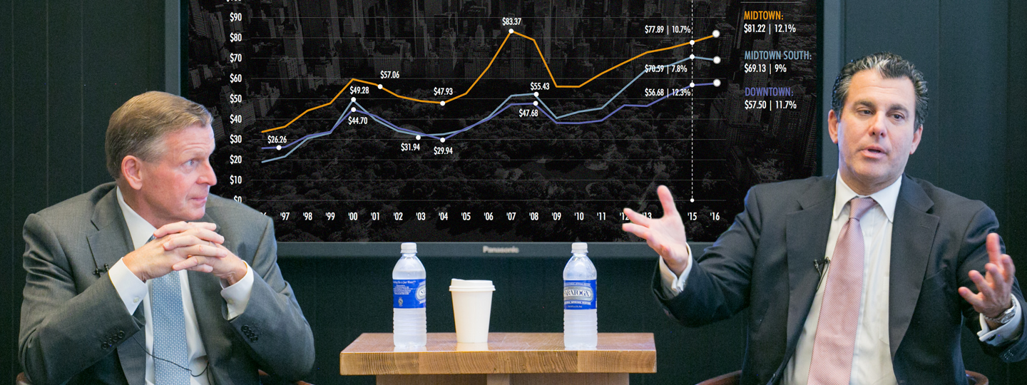 2 men in suits discussing a chart of pricing data